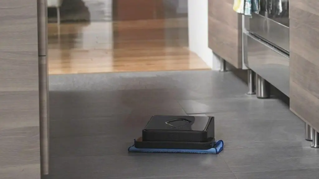 The robotic mop on tiled floor with wooden floor in the background of this iRobot Braava 380t review