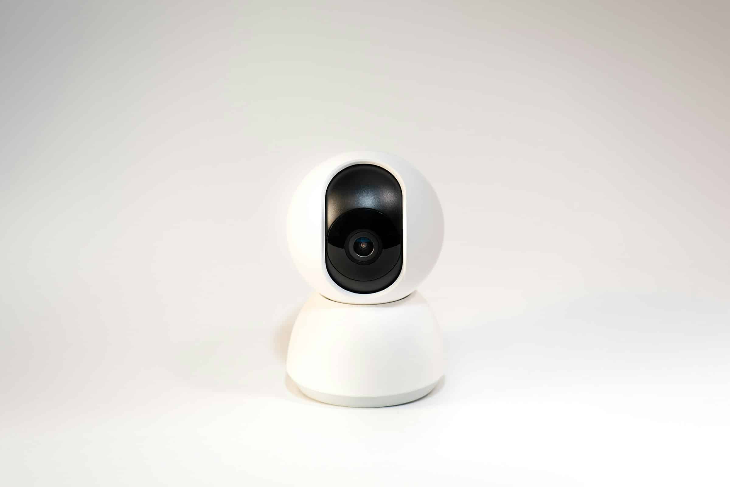 A small white pan-and-tilt home security camera on a plain white surface