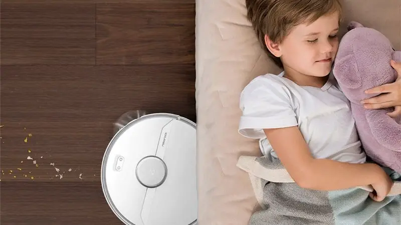 The Roborock S6 cleaning up under a sofa while a child sleeps