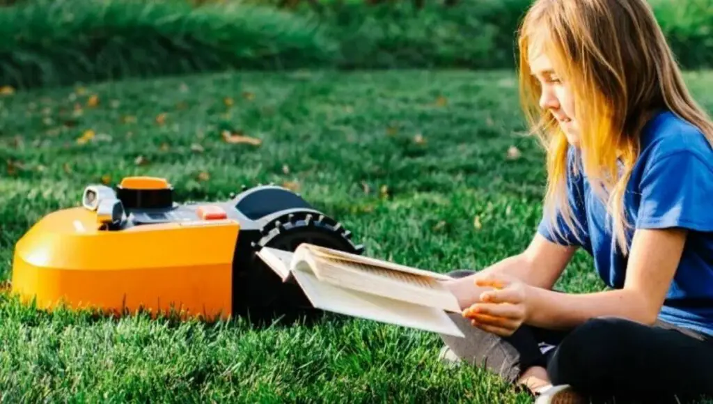 Worx wr140 robotic lawn mower and a baby read her book in the garden.