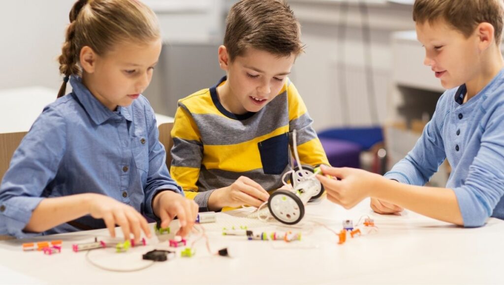 Happy children building coding robots at robotics school