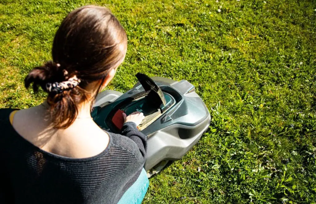 A lady using the control panel on a robot lawn mower