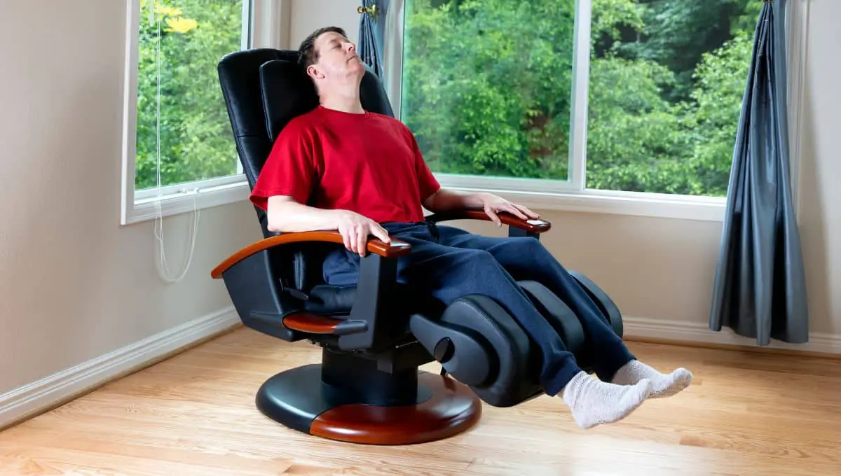 Mature man relaxing in home massage chair for pain relief in back and legs