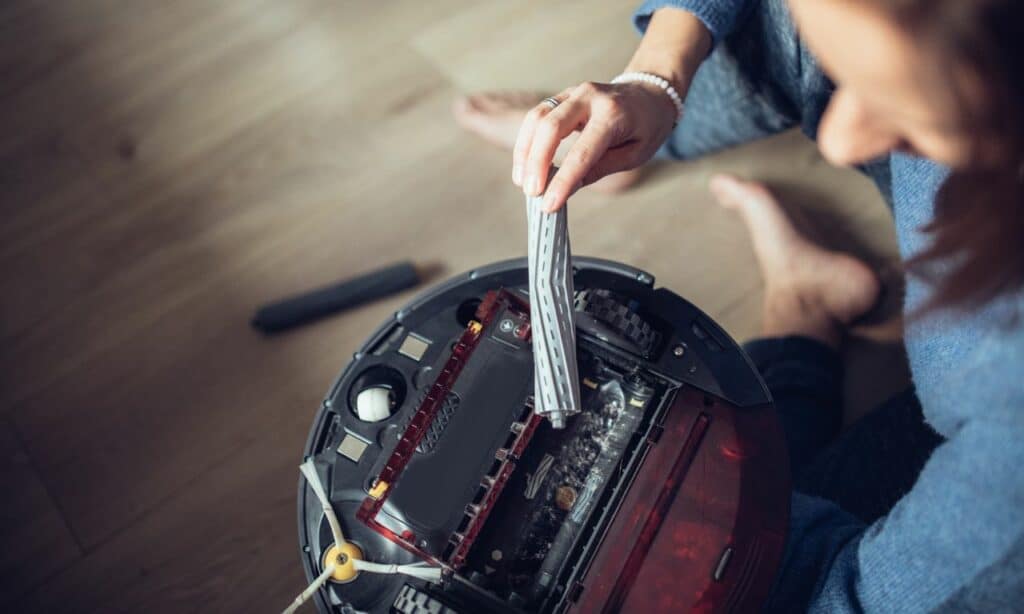 A lady removing the main brush from one of the Quietest Robot Vacuums